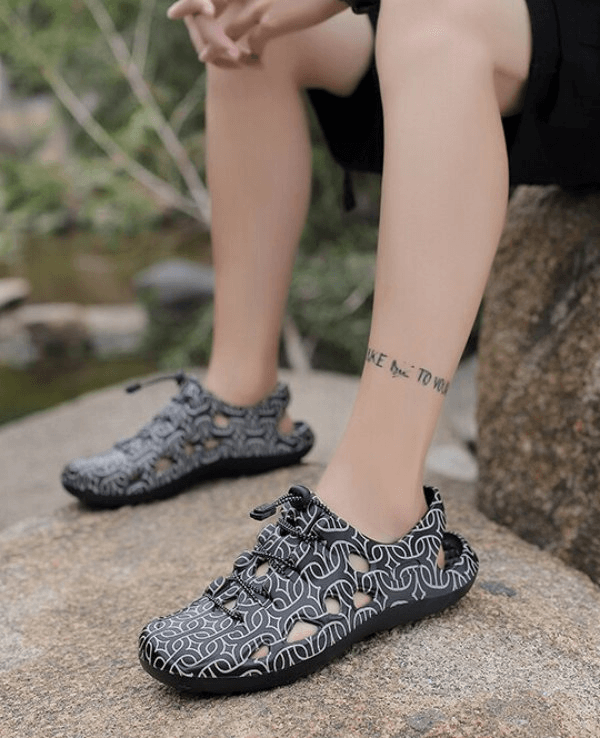 Person wearing stylish black patterned clogs perfect for beach and casual outings, featuring lightweight and quick-dry design.